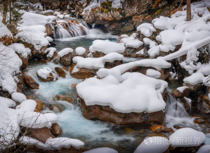 俄罗斯泰伯丁斯基保留地冬季用覆盖着雪的石头组成的高山河的清澈水流