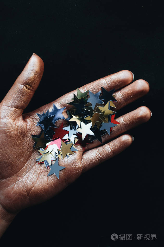 女性手拿星星纸屑黑色背景