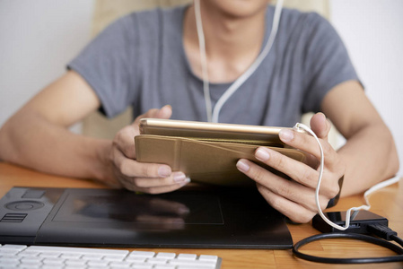 年青人数码平板电脑,内置耳机,可供坐桌的年青人使用照片