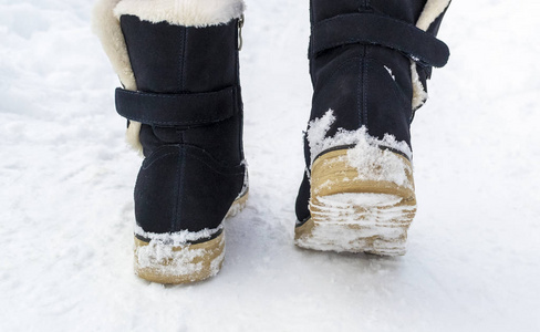 女性脚在黑色靴子走在冬天雪