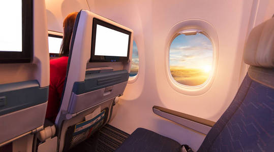飞机内部有排座椅和空白触摸娱乐屏幕。 快速旅行和新技术的概念。