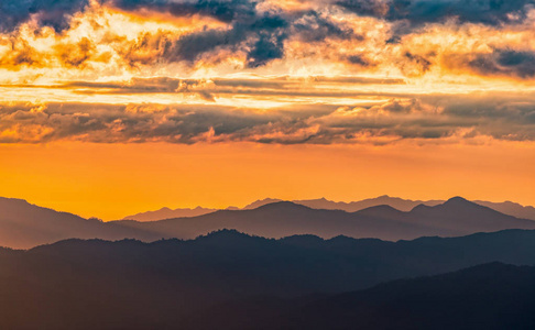 戏剧性的云浮在黑暗的山脉上，金色的天空在泰国香麦日落前。