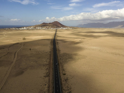 西班牙兰萨罗特加那利岛沙漠景观的鸟瞰图。 穿过沙漠的道路。 黑色沥青的舌头切割沙漠土地。 地平线上的浮雕。 火山。