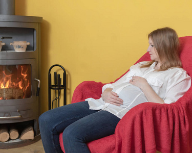 孕妇在家里的火炉旁坐在椅子上休息