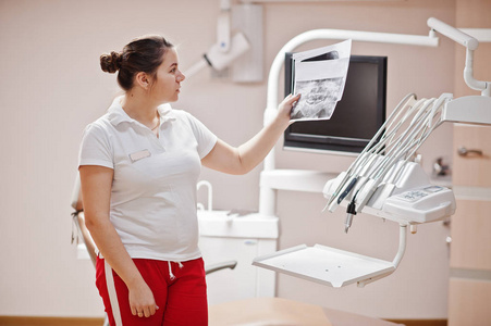 女牙医的肖像站在她的牙科办公室看x射线照片。