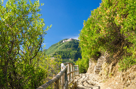 行人徒步旅行石径小径，康尼格利亚和弗纳扎村之间的栏杆，绿树蓝天背景国家公园Cinterre laspezia省利古里亚意大利