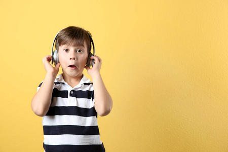 可爱的小男孩在彩色背景上用耳机听音乐。文本空间
