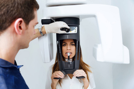 一名年轻英俊的牙医在牙科诊所拍摄了一张女性牙科X光照片。