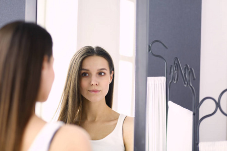 看自己在家里的镜子中反射的年轻女人照片