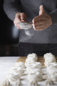 棉花糖的制作过程。 用金属筛把厨师的手关起来，在糕点店的厨房里用粉状糖洒上拉链。 糖果洒糖粉糖果