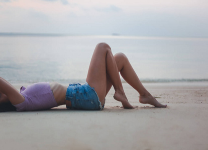 年轻美丽苗条的女人躺在沙滩上，美丽时尚休闲和旅游理念