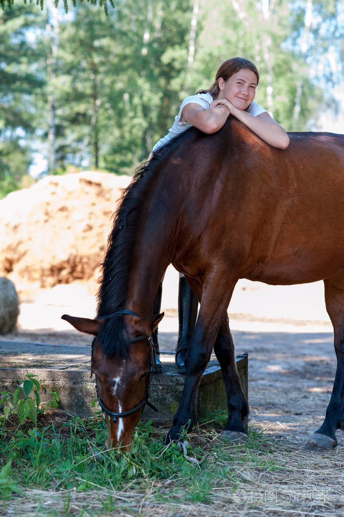 年轻的青少年快乐的女孩马术拥抱她最喜欢的栗色马.