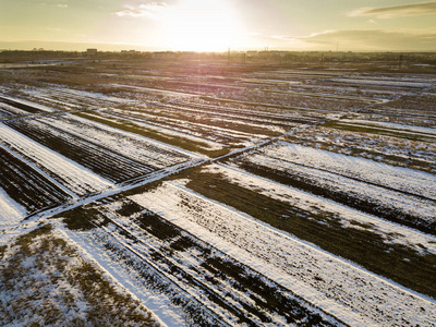在阳光明媚的冬日，空旷的雪田的顶部点缀着黑暗的地平线和明亮的天空。 航空无人机摄影概念。