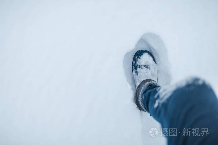在雪地上行走的男性腿的俯视图