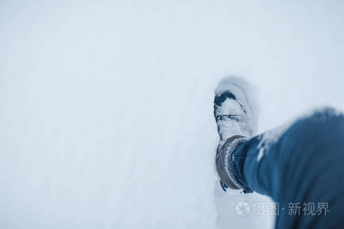 在雪地上行走的男性腿的俯视图