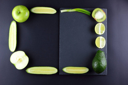 绿色水果和蔬菜黑色背景与创意复制空间。 框架从天然产品绿色。 鳄梨猕猴桃石灰和苹果在石板上。 顶部视图