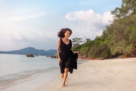 年轻美丽快乐的女人穿着时尚的裙子，欢快地沿着海滩奔跑，美丽时尚休闲和旅游的理念