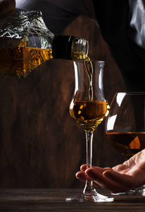 酒保在旧酒吧柜台上用小玻璃杯倒酒.