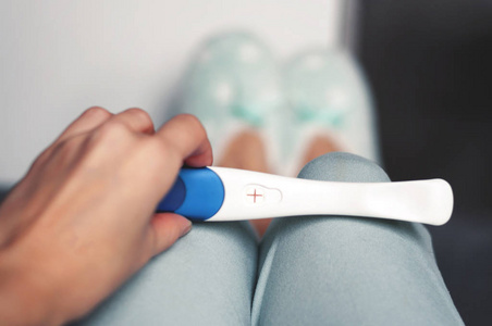 女孩手里拿着阳性的孕检.新生活的概念.选择性对焦照片