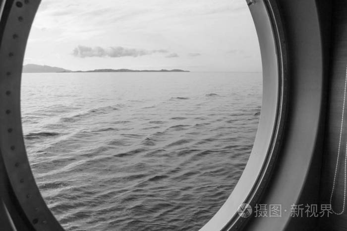 游船上的圆形门廊通过海岸和大海的窗户的内部视野日出对海特写镜头