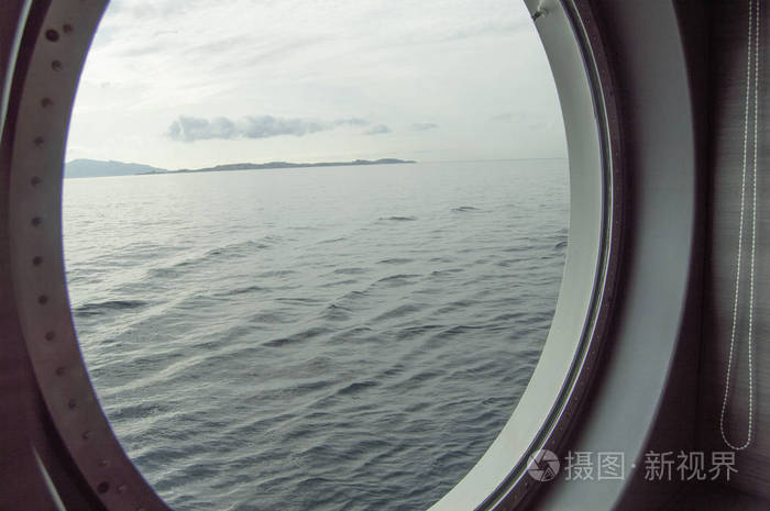 圆形舷窗上的游轮内景通过海岸的窗户和海上日出靠海接近