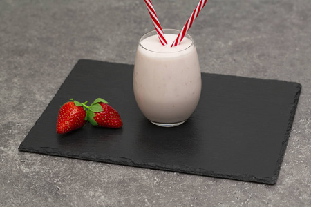草莓奶昔或冰沙在玻璃罐黑色石板背景。减肥有机食品。复制空间。