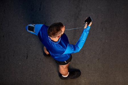 跑步者站在街上使用智能手机的俯视图. 健康的生活方式概念.照片