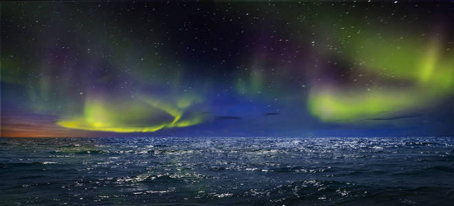 地球北部美丽的北极光。 壮丽的海景和北极光与岩石。 美丽的海水嬉戏，色彩和光线