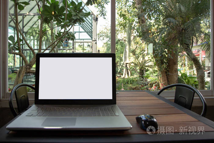笔记本电脑与空白白色屏幕模拟模板背景在桌子上，以查看日出山上。