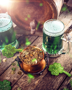 s Day symbols gree beer, clover leafs and coins on wooden backgr