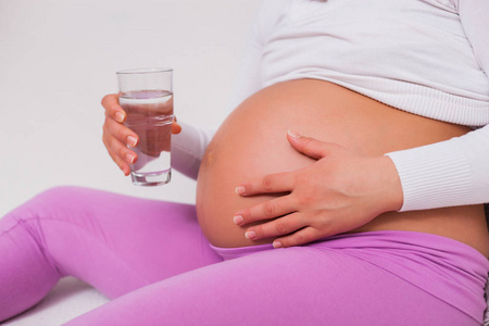 孕妇拿着一杯水。