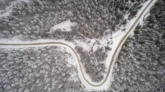 冬季森林的鸟瞰。 来自空气的自然冬季景观。 雪下的森林是冬天的时候。 雾蒙蒙的雪山的鸟瞰。 田园诗般的冬季景观中道路的鸟瞰。