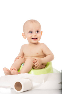 婴儿微笑着坐在白色背景上的便盆上。 用于文本或设计的横幅。