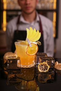 酒吧老板做酒精鸡尾酒。 新鲜酒精青霉素鸡尾酒加橙色片和冰块