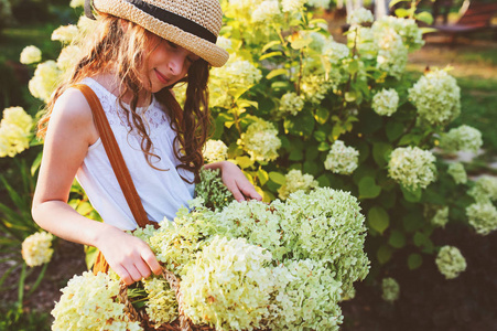 快乐浪漫的女孩在阳光明媚的夏日花园采花