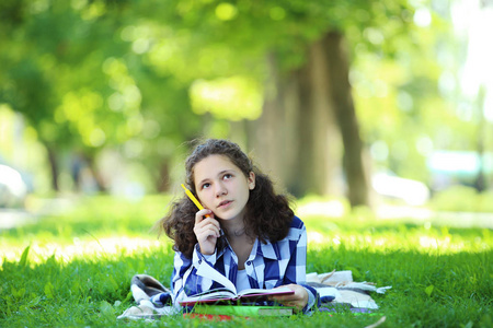 躺在公园里有书的年轻女孩