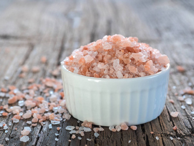 粉红色喜马拉雅盐在白色盐摇床上的木制背景。 健康香料特写