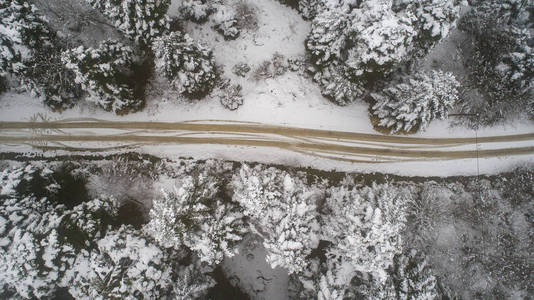 冬季森林的鸟瞰图。自然冬季景观从空中。森林下着雪是冬季.鸟瞰多雾多雪的冬山..田园冬季景观中道路的鸟瞰。