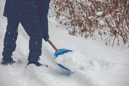 一个拿着铲子的人在雪地上清扫道路