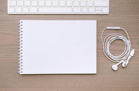 工作背景一个笔记本，键盘和耳机放在木桌上