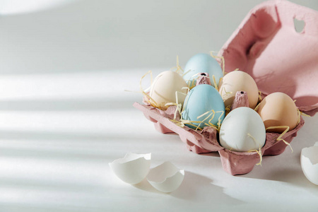 天然彩色棕色和白色鸡蛋在鸡蛋盒与阳光。成分在糊状颜色。 复活节康塞普特。