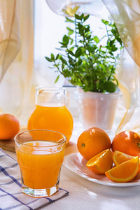 一杯橙汁，早上在窗边的桌子上放新鲜的橘子