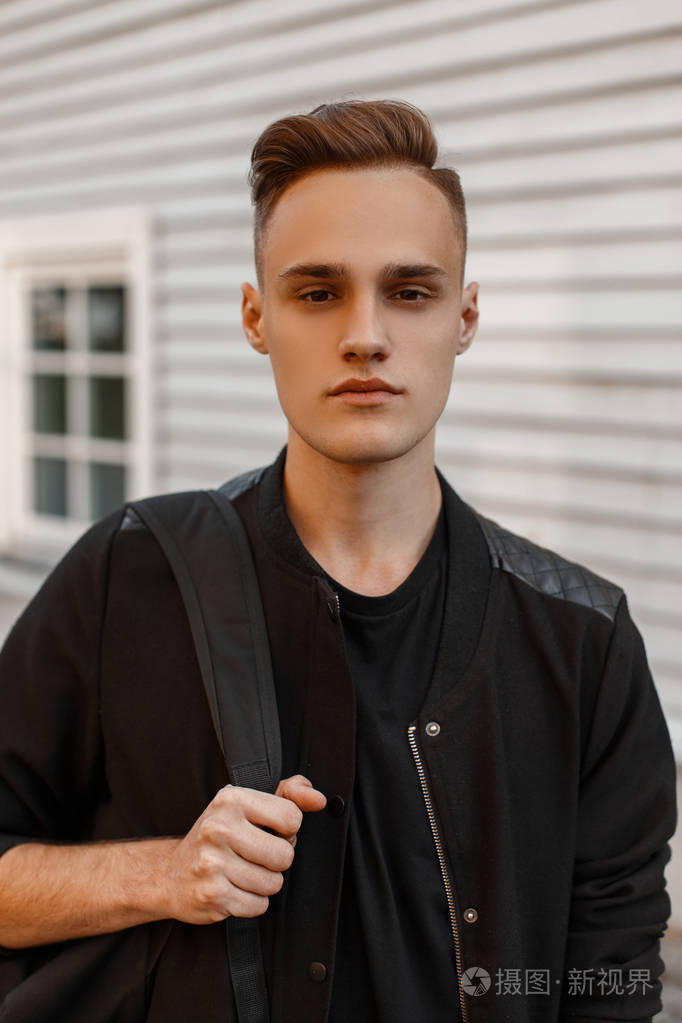 一个英俊的年轻人的肖像,一个时尚的发型,穿着一件黑色的夏季夹克,穿