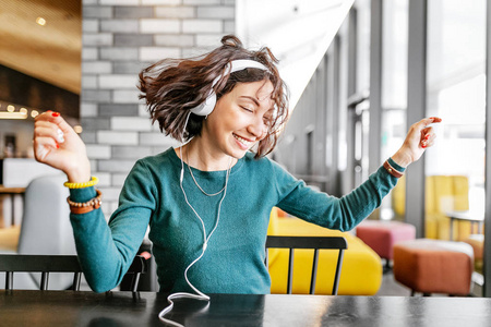 年轻快乐的女人戴着耳机，通过Wi Fi网上收听她最喜欢的歌曲