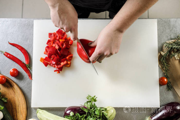 男厨师在一家穿着黑色围裙的餐馆里切蔬菜做沙拉白色