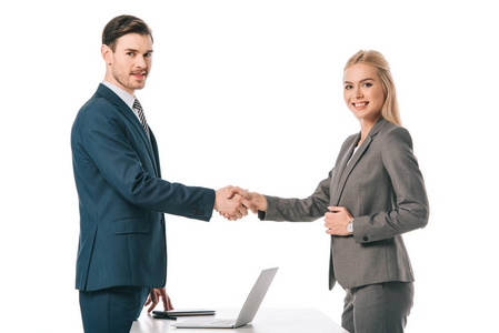 成功的商人握手，在工作场所与白色笔记本电脑打交道