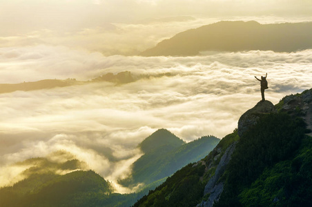 宽山全景。 游客的小轮廓与背包在岩石山坡上，举起手在山谷上覆盖着白色的蓬松云。 自然之美旅游之美和旅游理念