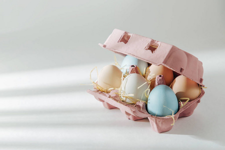 天然彩色棕色和白色鸡蛋在鸡蛋盒与阳光。粉彩的组成。复活节。