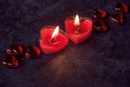 两支红色心形蜡烛,黑暗背景下的情人节装饰照片