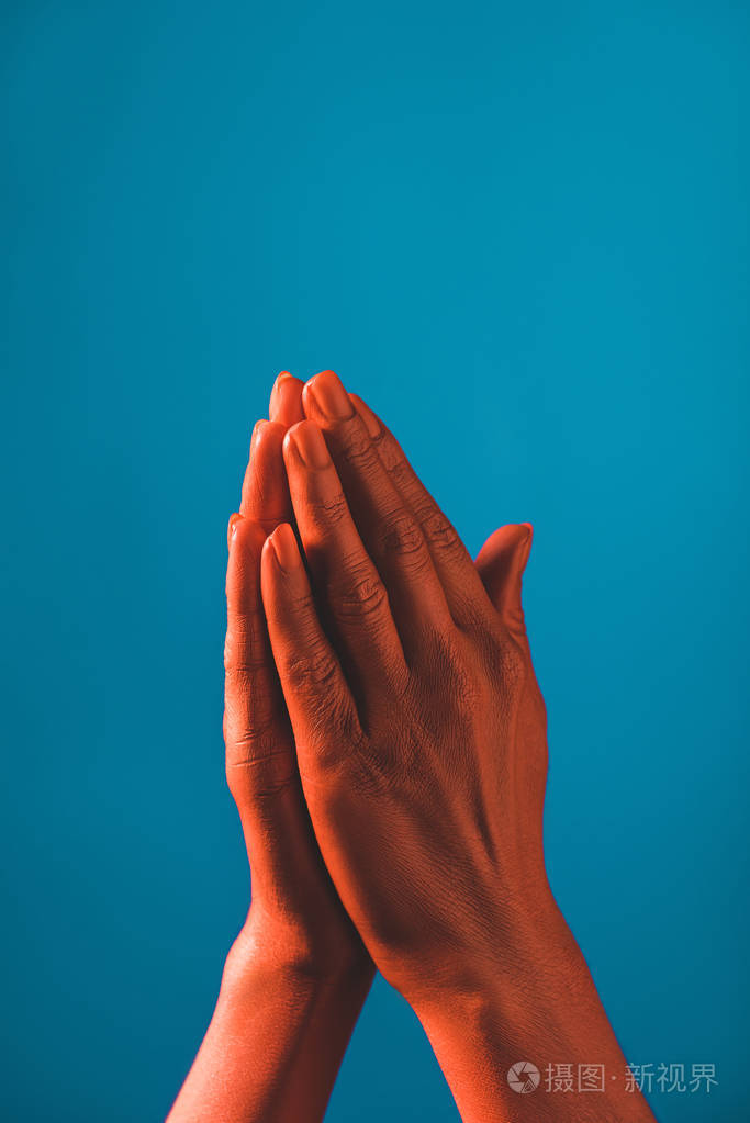 部分观看妇女显示祈祷标志珊瑚色的手在蓝色背景,颜色的2019年概念